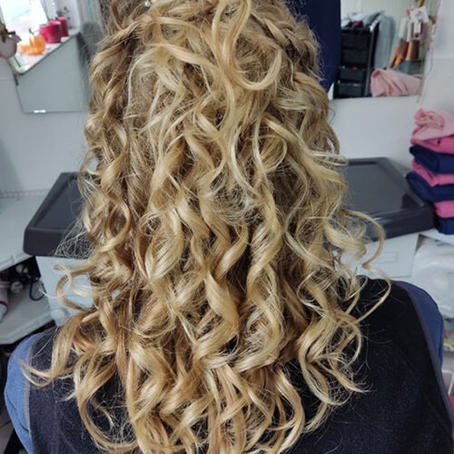 Lockige blonde Haare, dekorative Haarnadel, von hinten gesehen.